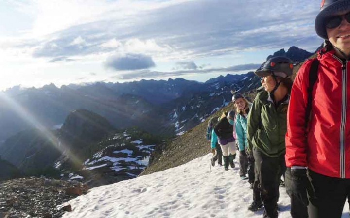 a group of women ascend a snowy trail on a mountaineering course with outward bound
